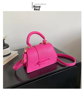Macro detail of fuchsia crossbody bag with litchi texture and gold metal hardware