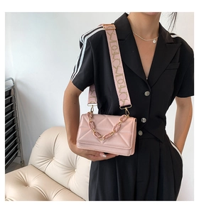 Detail of pink quilted crossbody bag featuring wide jacquard strap and acrylic chain