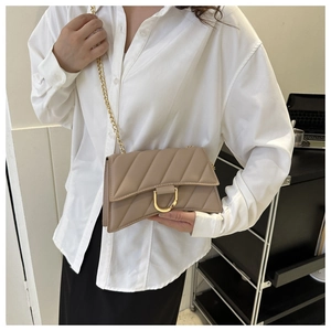 Close-up of beige quilted hourglass bag with gold chain and D-ring buckle on model