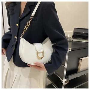 Gros plan d'un sac demi-lune blanc avec boucle en U dorée porté par un mannequin