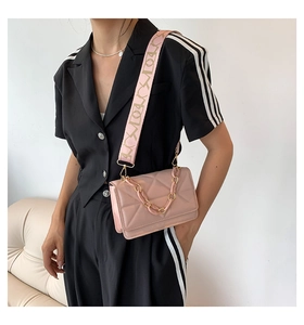 Detail of pink quilted shoulder bag with acrylic chain and wide patterned strap on model