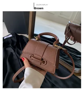 Detailed view of brown lychee grain leather square bag with gold hardware buckle