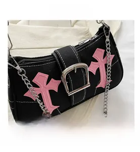 Close-up of black canvas bag featuring pink cross embroidery and silver chain strap detail