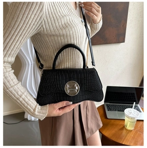 Détail de la texture crocodile noire et du fermoir en métal argenté sur le sac à main