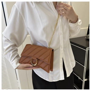 Close-up of brown quilted crossbody bag featuring a gold U-shaped buckle and metal chain