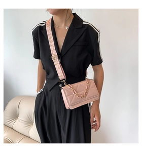 Detail of pink quilted crossbody bag with golden chain and wide printed textile strap
