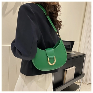 Gros plan d'un sac demi-lune vert avec boucle dorée en D porté par un mannequin