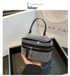 Detail of black handbag with silver rhinestones, chain strap, and elegant gift packaging