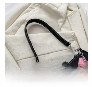 Close-up of black canvas shoulder bag with pink star patch and silver buckle detail