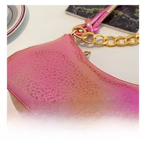 Detail of pink snake-patterned leather texture with chunky gold chain on a handbag