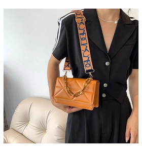 Detail of caramel crossbody bag featuring diamond quilted texture and wide bicolor strap