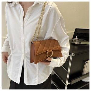 Close-up of caramel quilted crossbody bag featuring a curved base and gold D-ring buckle