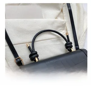 Detail of black crocodile texture handbag with unique knotted handle and gold metal hardware
