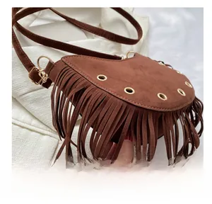 Detail of brown suede crescent bag with hanging fringe and gold eyelet decorations