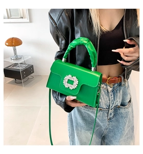 Detail of emerald green handbag featuring crystal square buckle and pleated handle