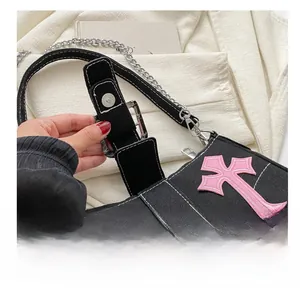 Detailed view of the metal magnetic clasp and pink cross embroidery on black canvas bag