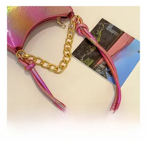 Detail of the holographic snake skin texture and gold chain strap on the handbag