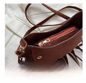 Detailed view of the smooth golden metal zipper on a dark brown suede tassel bag