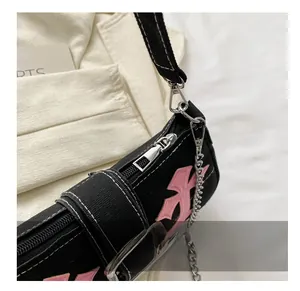 Detail shot of smooth metal zipper and pink embroidery on black canvas shoulder bag