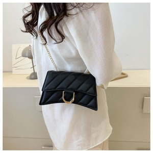 Close-up of quilted black crossbody bag with gold chain strap worn by a model