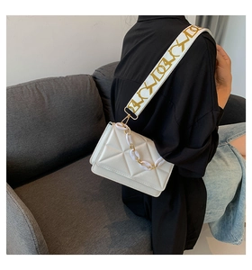 Detail of white geometric textured crossbody bag with chunky chain and pattern strap