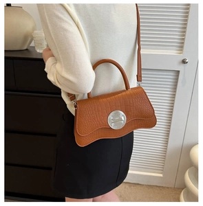 Sac à main marron avec motif crocodile montrant la taille sur un mannequin femme