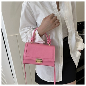 Detail of pink crocodile embossed handbag with a decorative knot handle and gold buckle