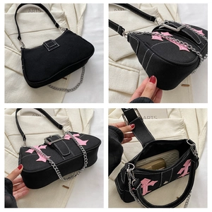 Detail view of gothic canvas baguette bag with pink cross patches and metal chain straps