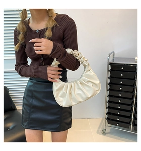 Chic white crescent handbag with ruched handle shown in a stylish lifestyle setting