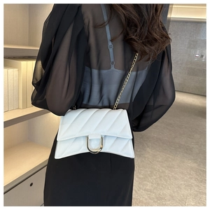 Rear view of model wearing a white quilted crossbody bag with gold D-buckle and chain