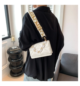 Detail view of the white quilted crossbody bag featuring a chunky chain and wide strap