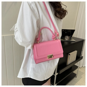 Detail of pink crocodile texture crossbody bag with gold metal buckle and leather strap