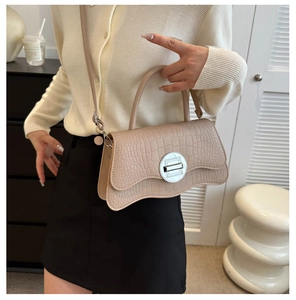 Détail du sac à main beige motif croco avec bord ondulé et fermoir en métal argenté