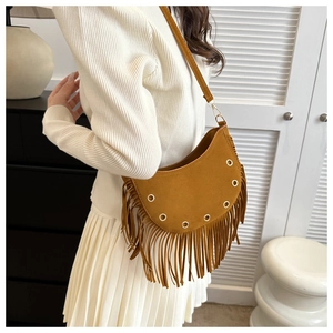 Detail view of brown suede crescent bag with hanging fringe tassels and metal eyelets
