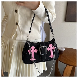 Detail of black canvas baguette bag with pink leather crosses and silver chain strap