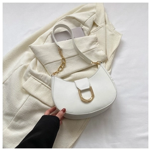 Détail du sac demi-lune blanc avec boucle D dorée et bandoulière chaîne sur un blazer