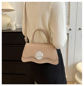 Détail d'un sac à bandoulière en cuir de crocodile beige avec boucle et bord ondulé
