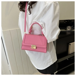 Detail of pink crocodile pattern leather bag with golden metallic lock and top handle