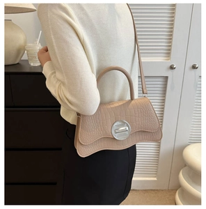 Détail du sac à main beige motif crocodile avec fermoir rotatif en métal et bandoulière
