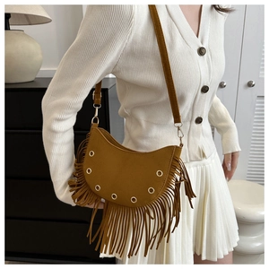 Detail showing brown suede crescent bag texture with stylish fringe and metal eyelets