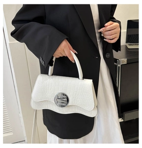 Détail du sac à main blanc motif crocodile avec rabat ondulé et boucle ronde argentée