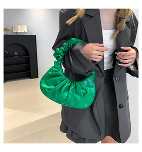 Close-up of bright green ruched crescent bag showing glossy leather texture and cloud pleats
