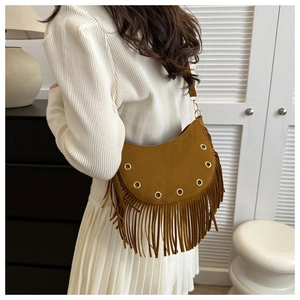 Close-up of brown suede saddle bag featuring metal eyelets and decorative long tassels