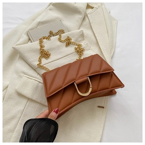 Detail of brown quilted shoulder bag featuring a gold D-buckle and metal chain strap