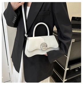 Gros plan du sac en cuir blanc à motif crocodile avec rabat ondulé et boucle argentée