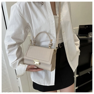 Detail of cream crocodile embossed small square bag with knotted handle and gold lock