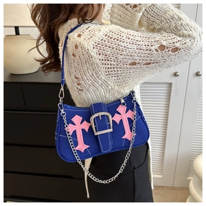 Detail of blue fabric underarm bag with pink cross embroidery and silver chain strap