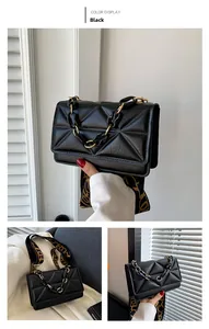 Detail of black quilted crossbody bag with gold chain handle and jacquard strap