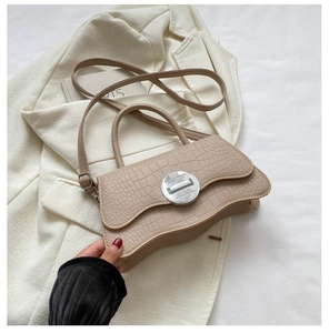 Gros plan du sac à main beige motif crocodile avec fermoir rotatif argenté élégant