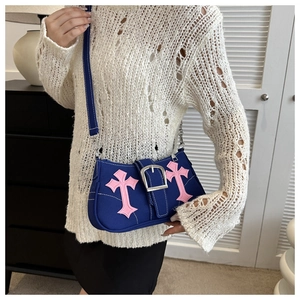 Detail of blue canvas bag with pink cross embroidery and large silver metal buckle strap